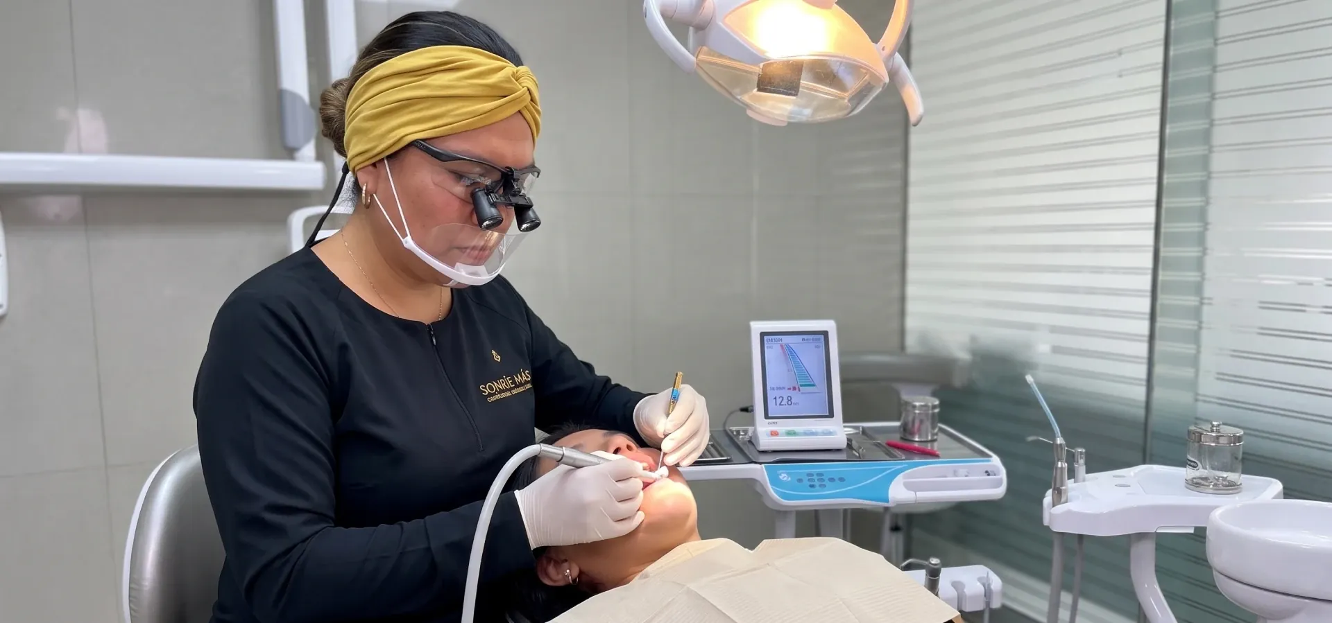 Odontóloga de Sonríe Más con lupas de aumento realizando una endodoncia con localizador de ápice