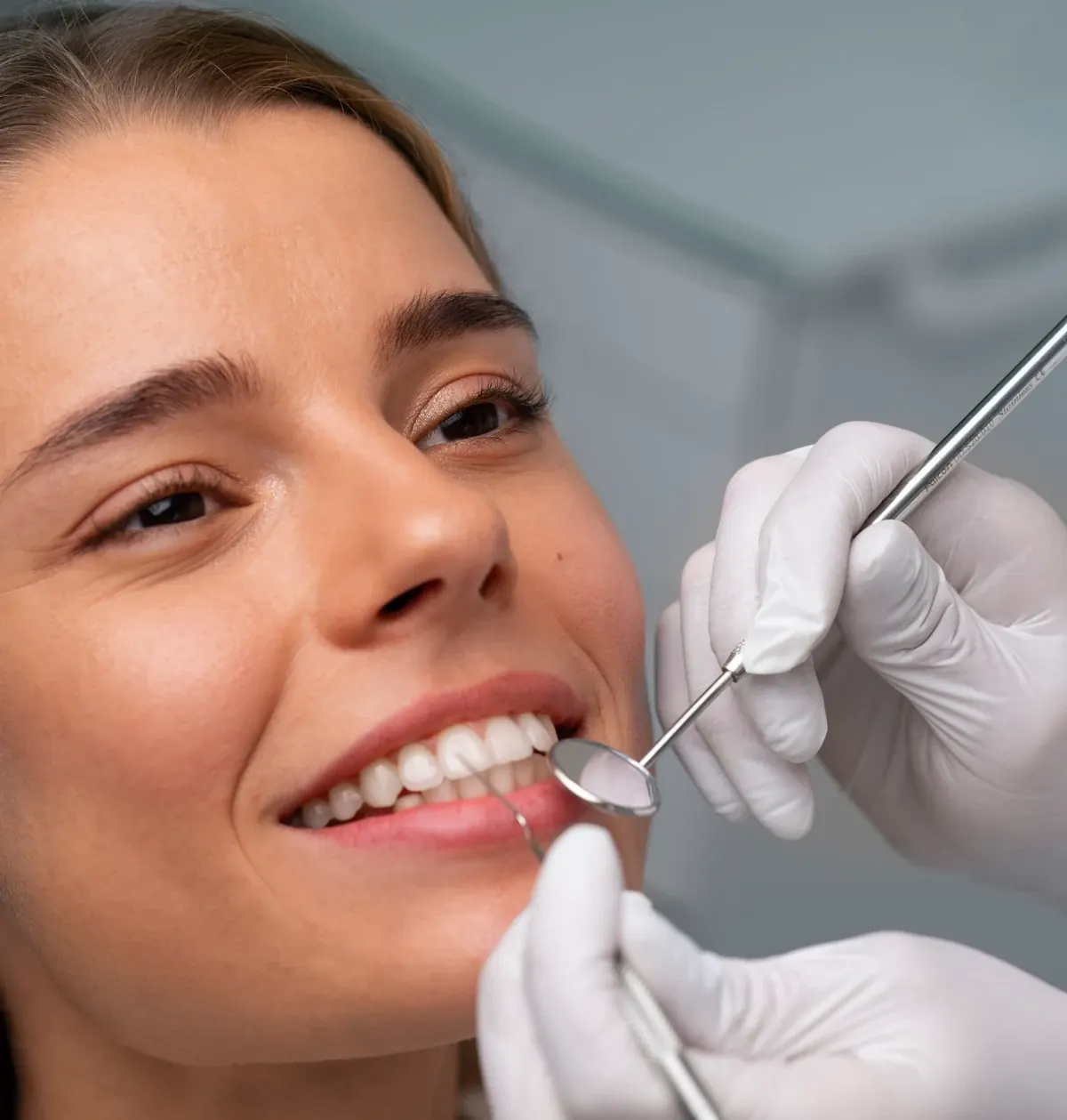 Paciente sonriendo durante una revisión dental con espejo bucal