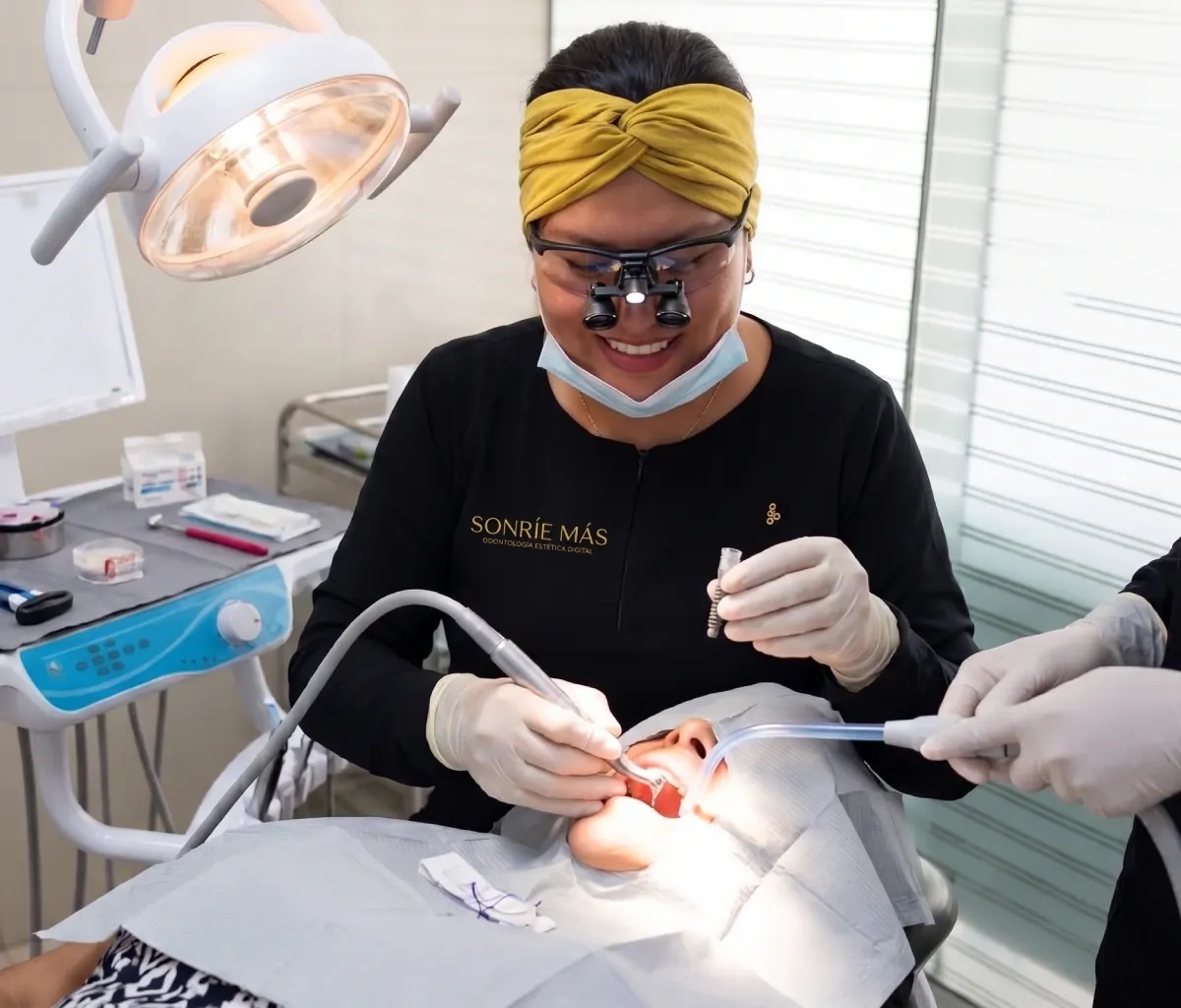 Odontóloga de Sonríe Más con lupas de aumento sosteniendo un implante dental durante el tratamiento